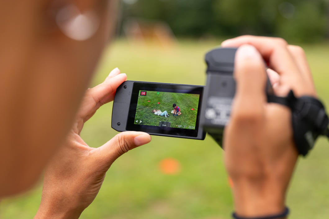 Panasonic HC-V900 camcorder capturing video footage, with a sleek black design and control buttons visible in the image.