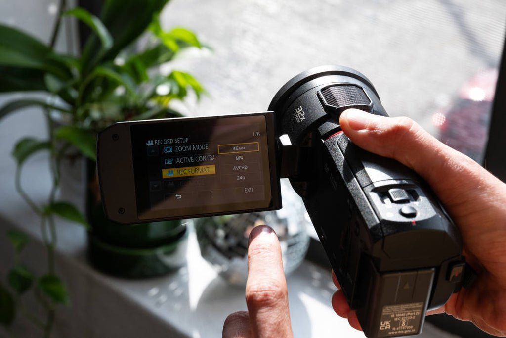 Panasonic HC-VX3 camcorder with 1060W lens, showing a person filming outdoors with a professional camera setup.