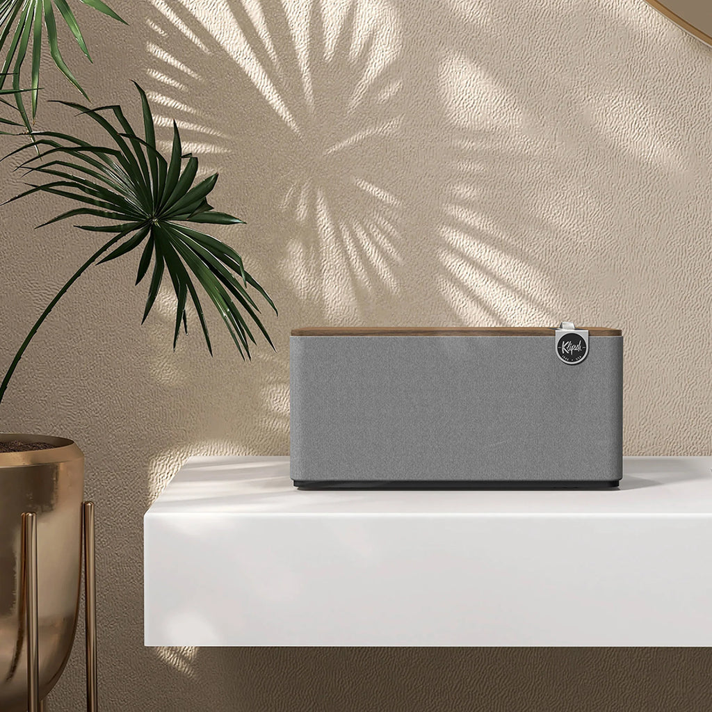 Klipsch The Three Plus wireless speaker with wooden cabinet and digital display, showcasing modern audio design and controls.