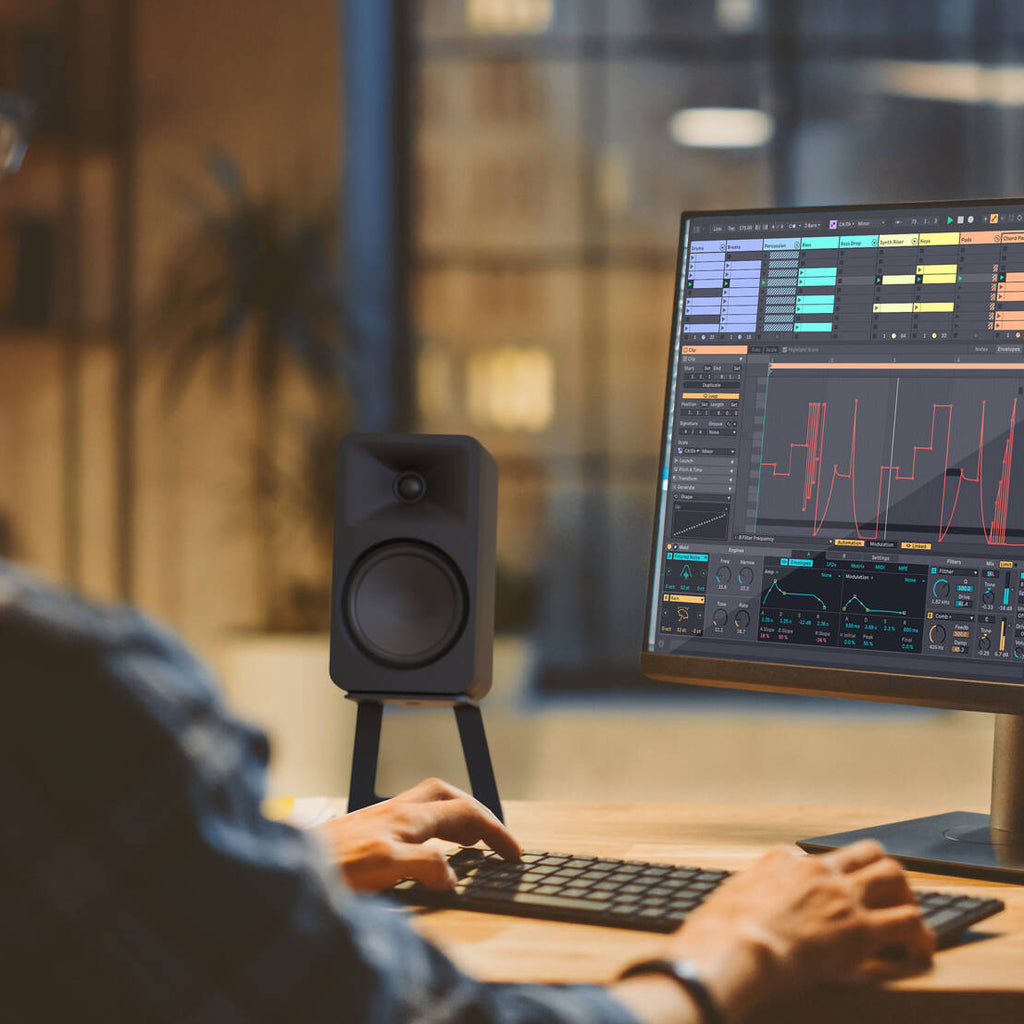Kanto Audio Ora 4 desktop speakers shown on a desk with a sleek black design and compact size.