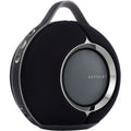 Devialet Mania portable speaker showing sleek design, control buttons, and fabric grille in a modern setting.