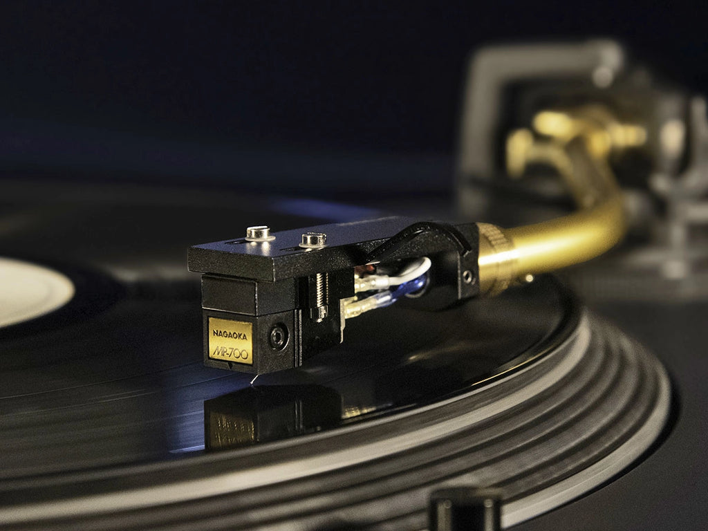 Nagaoka MP-700H turntable cartridge with headshell mounted on a vinyl record, showing detailed stylus and cartridge body.