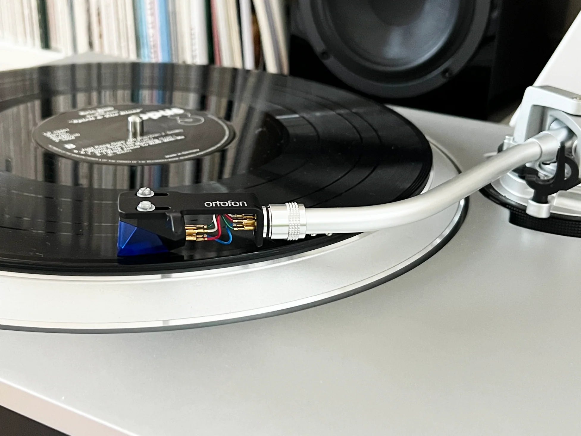 Ortofon 2M Blue cartridge mounted on a turntable, showcasing the high-quality stylus for vinyl record playback.