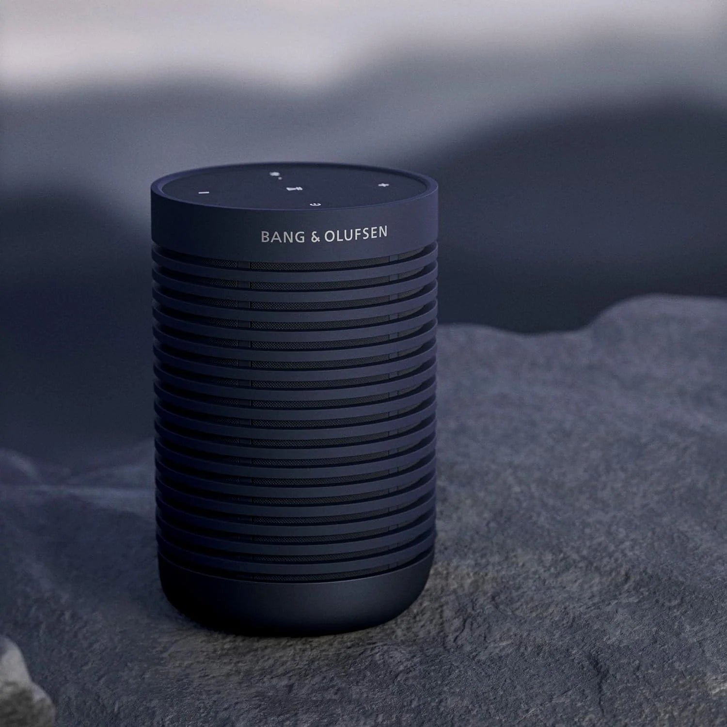 Bang & Olufsen Beosound Explore portable speaker with rugged design, black color, and textured fabric exterior.
