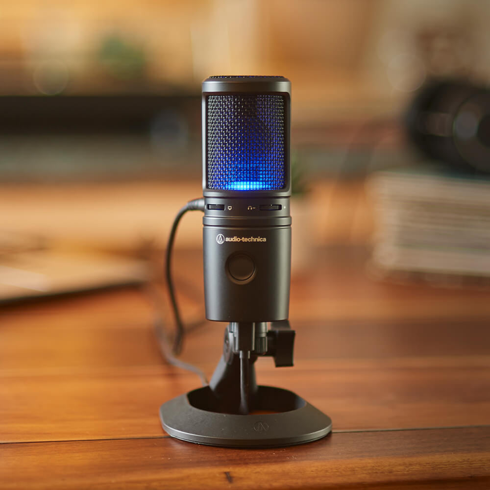 Audio Technica AT 2020 USB-X microphone on a desktop setup, showcasing a professional USB condenser microphone for streaming or recording.