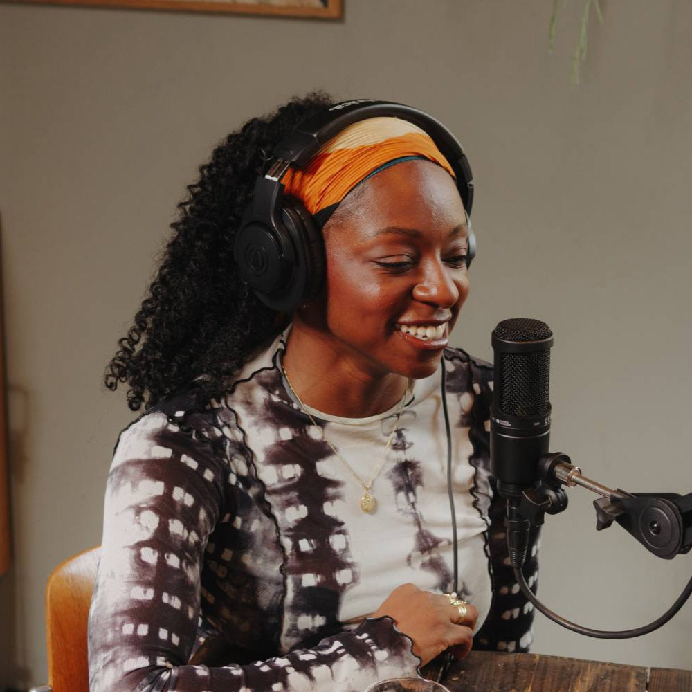Audio Technica AT 2020 condenser microphone displayed on a desktop, with a professional setup and pop filter in a recording studio environment.