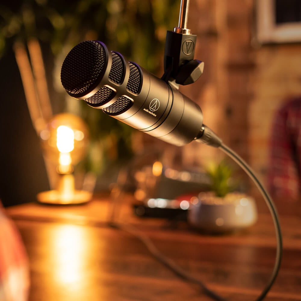 Audio Technica AT2040 dynamic microphone shown in a professional studio setup with a pop filter and microphone stand.