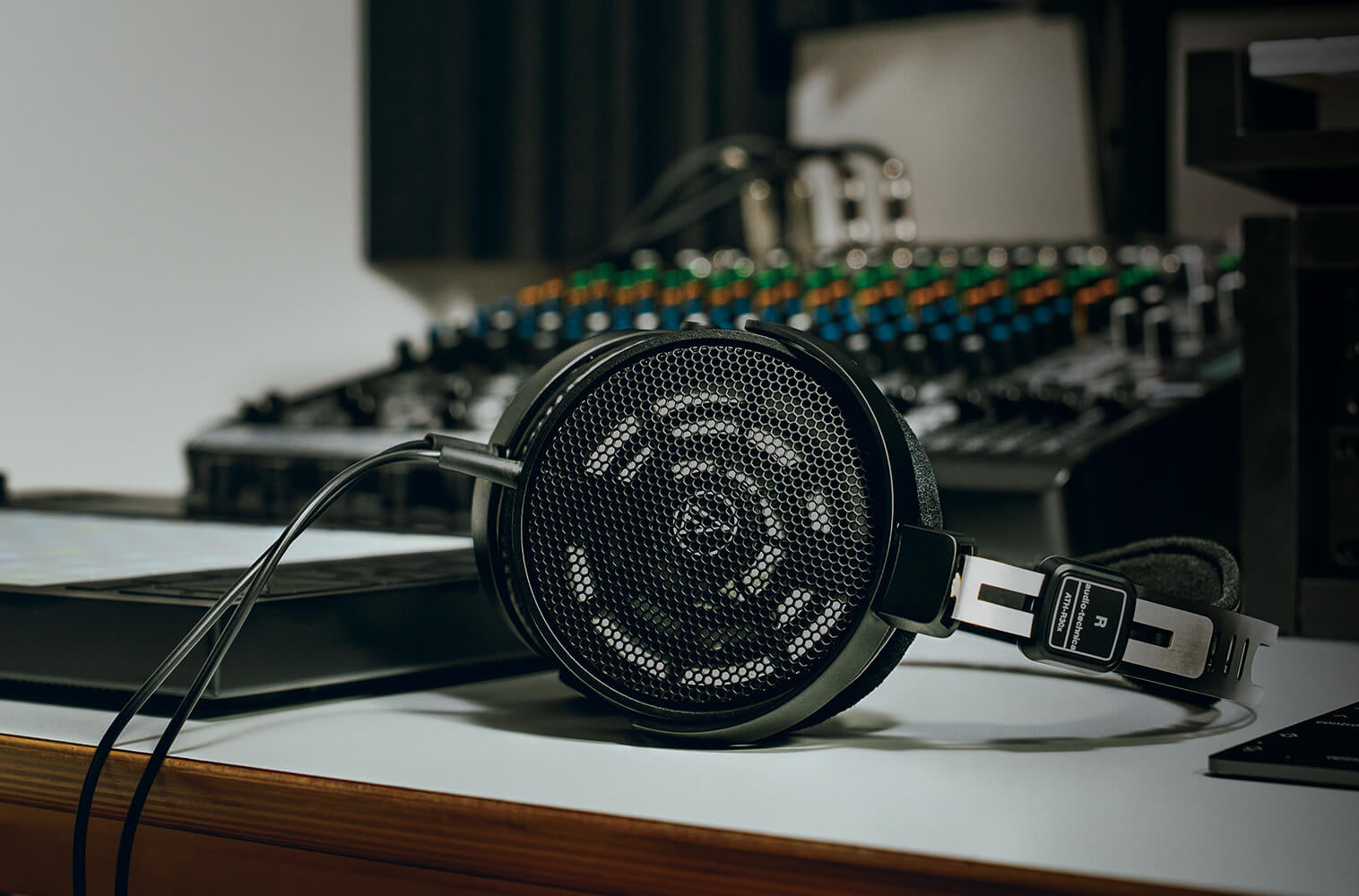 Audio Technica ATH-R30x studio headphones shown in a lifestyle setting with a modern workspace and open-back design.