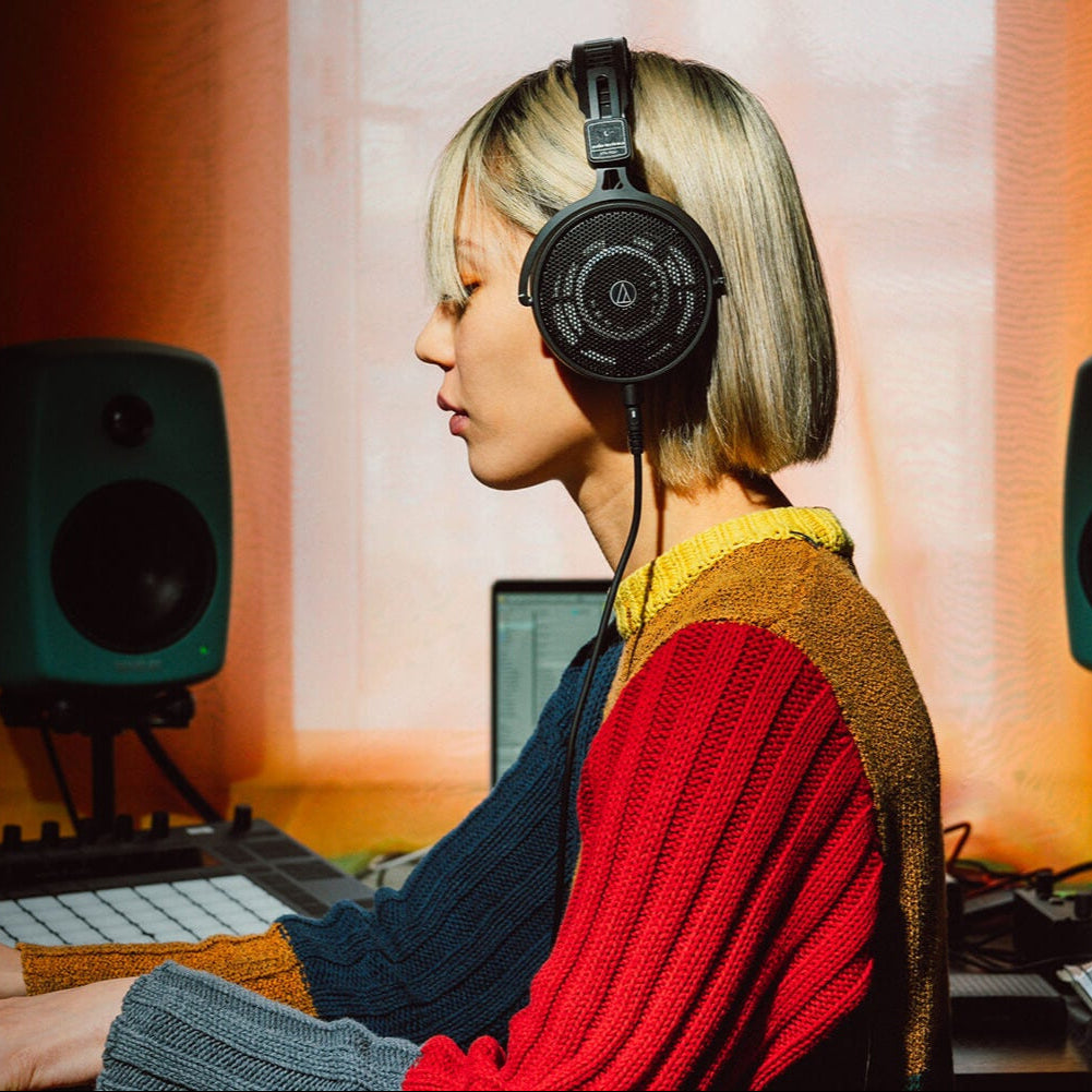 Audio Technica ATH-R50x studio headphones displayed on a lifestyle banner, showcasing their sleek design and over-ear construction.