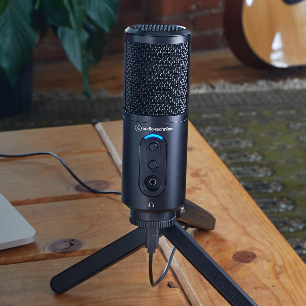 Audio Technica ATR2500x-USB USB microphone displayed on a desktop, showing its compact design and connection port.