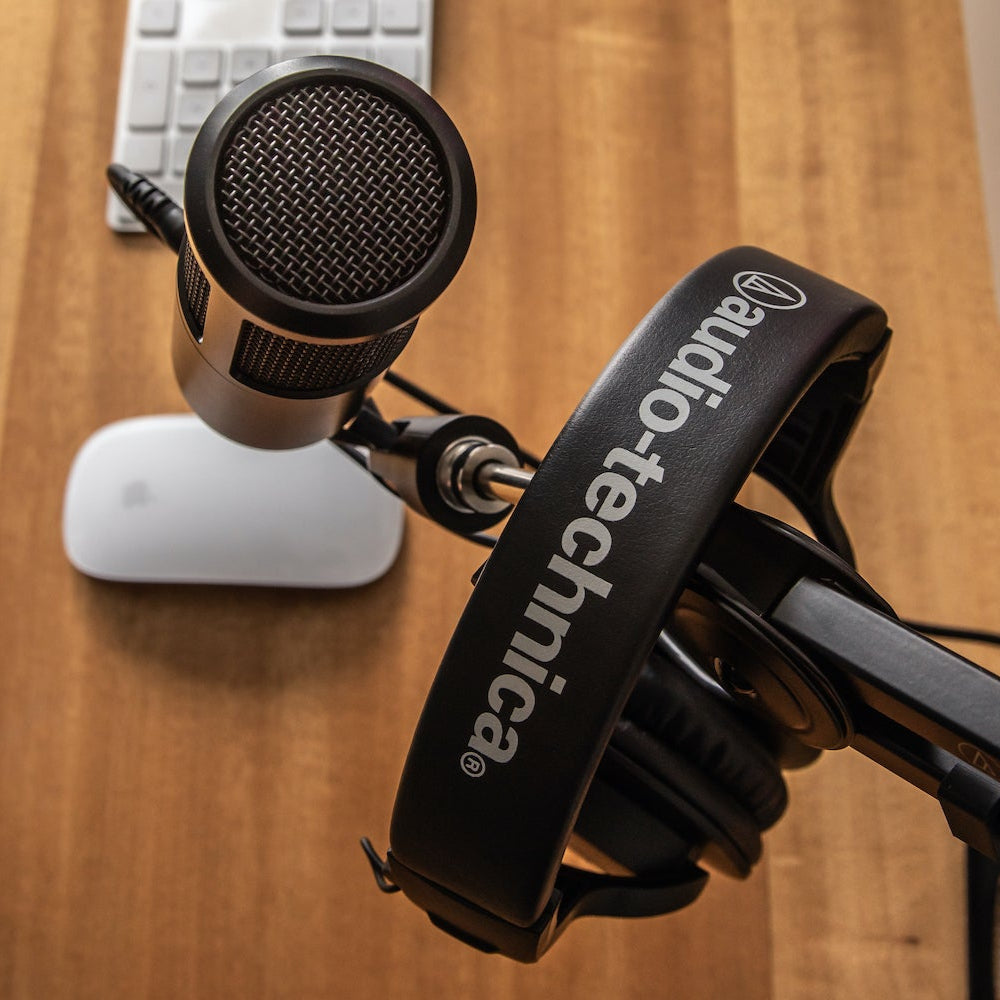 Audio Technica ATH-M20x studio headphones shown on a home office desk, featuring over-ear design and black finish.