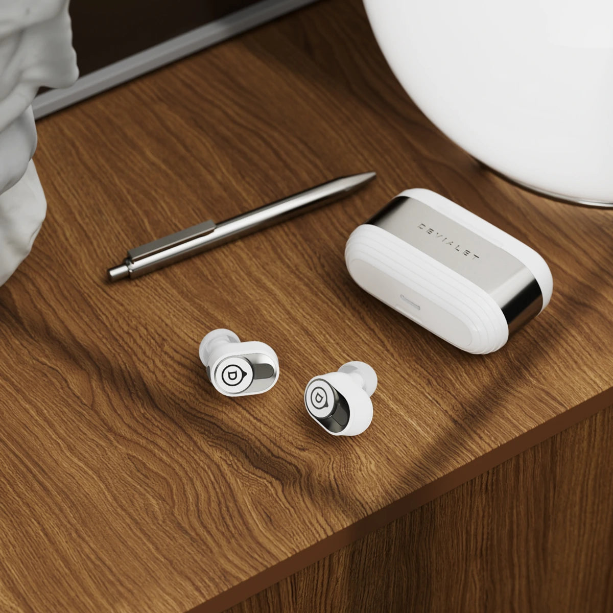 White Devialet Gemini II wireless in-ear headphones with sleek design and compact charging case.