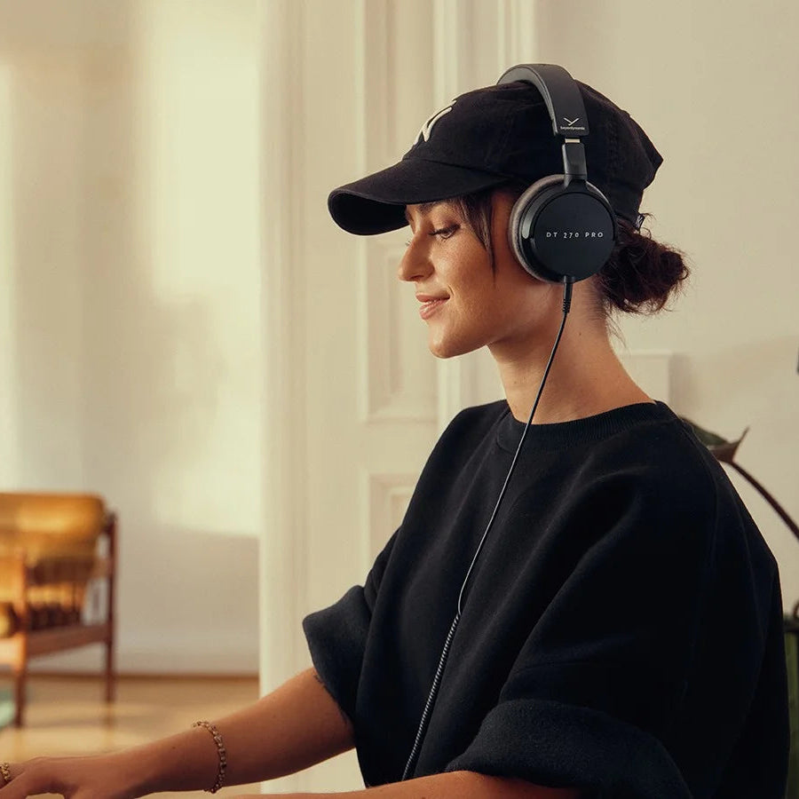Beyerdynamic DT 270 Pro studio headphones with black ear cups and adjustable headband, worn by a person playing piano.