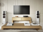 DALI Rubikore 6 passive floorstanding speakers shown in a modern living room setup, showcasing sleek black design and wood finish.