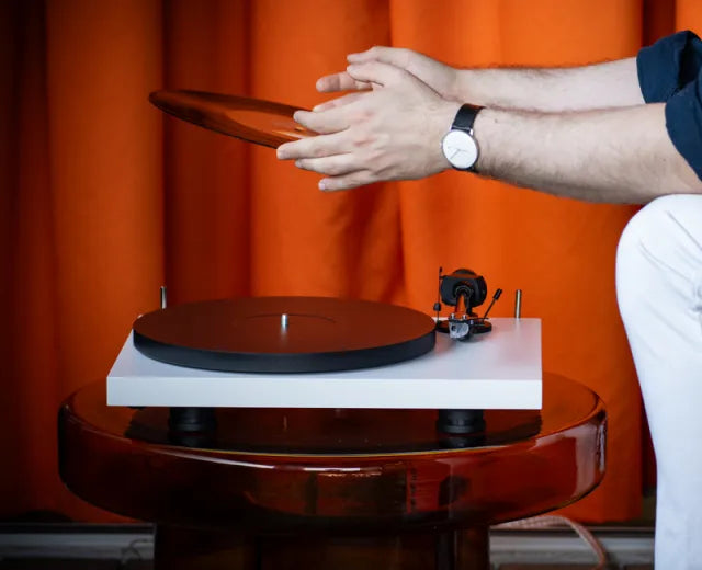 Pro-Ject Debut EVO 2 white turntable with sleek design and tonearm, set on a modern listening setup.
