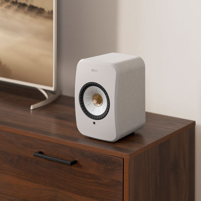 KEF LSX II active bookshelf speakers in Amber Haze with white cotton cloth grille, showcasing sleek modern design.