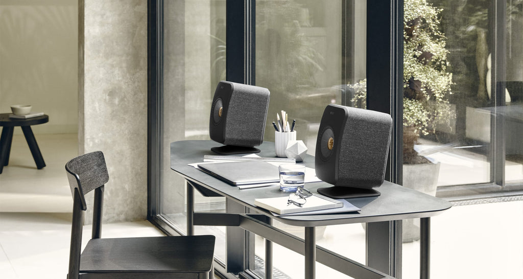 KEF P1 desk pad used as speaker stands, with the LSXII-20 speaker on top, showcasing a sleek modern design.