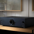 Onkyo Icon A-50 stereo amplifier in black beside a turntable in a stylish listening room setting.