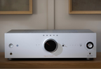 Close-up of the silver Onkyo Icon A-50 stereo amplifier on a modern cabinet, showcasing its sleek design and control knobs.