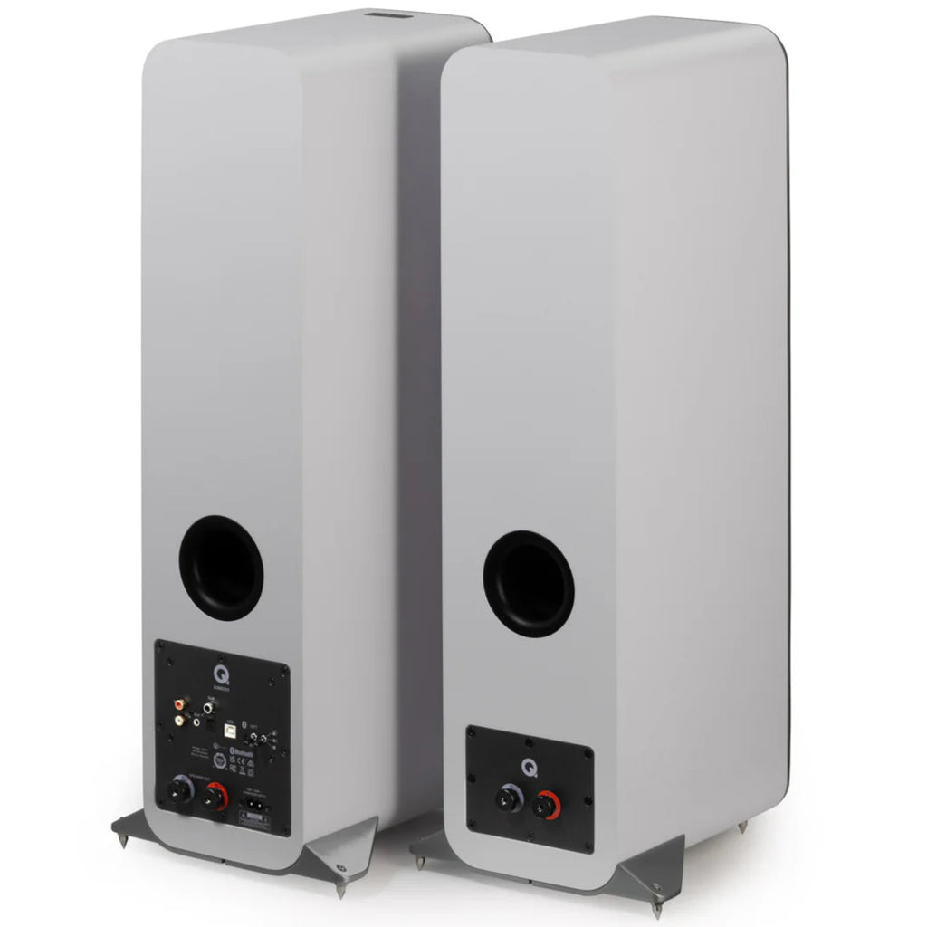 Pair of Q Acoustics M40 wireless speakers shown from rear angle, featuring a sleek white design and angled positioning.