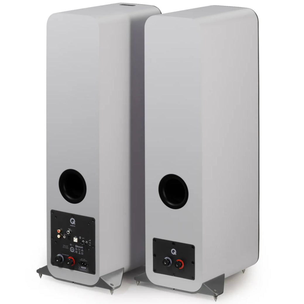 Pair of Q Acoustics M40 wireless speakers shown from rear angle, featuring a sleek white design and angled positioning.