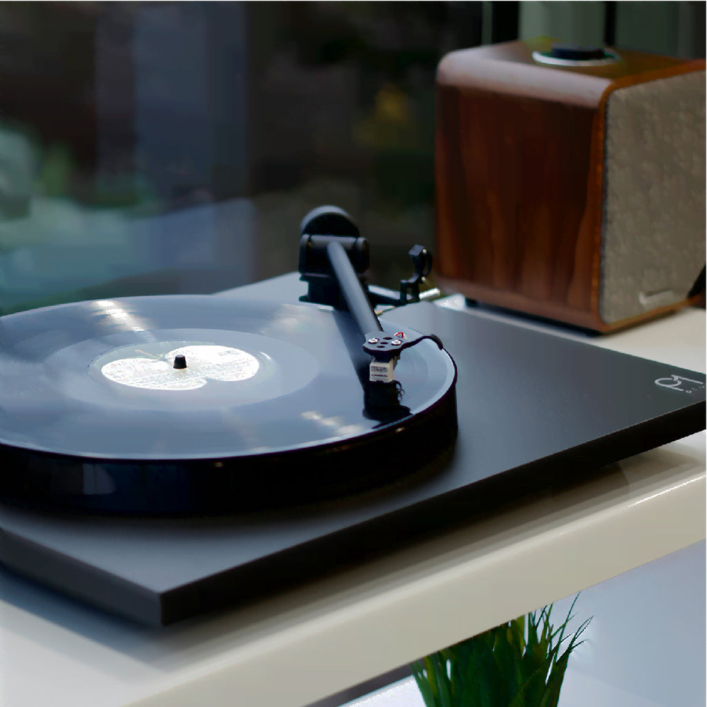 Rega Planar 1 Plus turntable with wooden plinth and tonearm, showcasing its sleek design and compact setup.