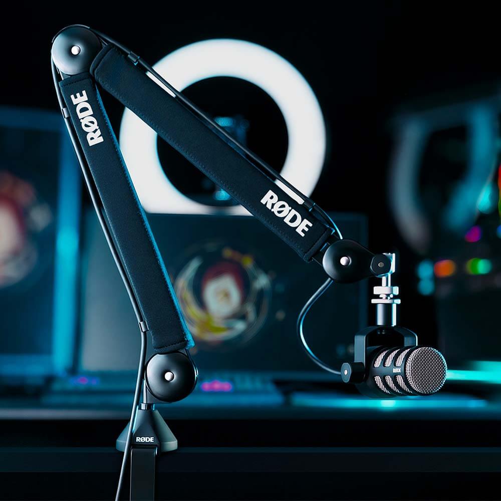 Rode PSA1+ broadcast microphone arm mounted in front of a gamer setup with gaming equipment and monitors.