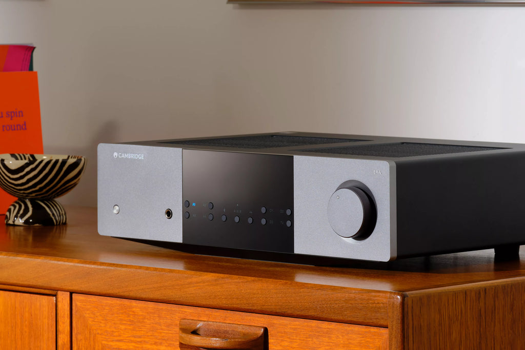 Cambridge Audio EXA100 stereo amplifier shown from a 3/4 angle, featuring a sleek black design with control knobs on the front panel.