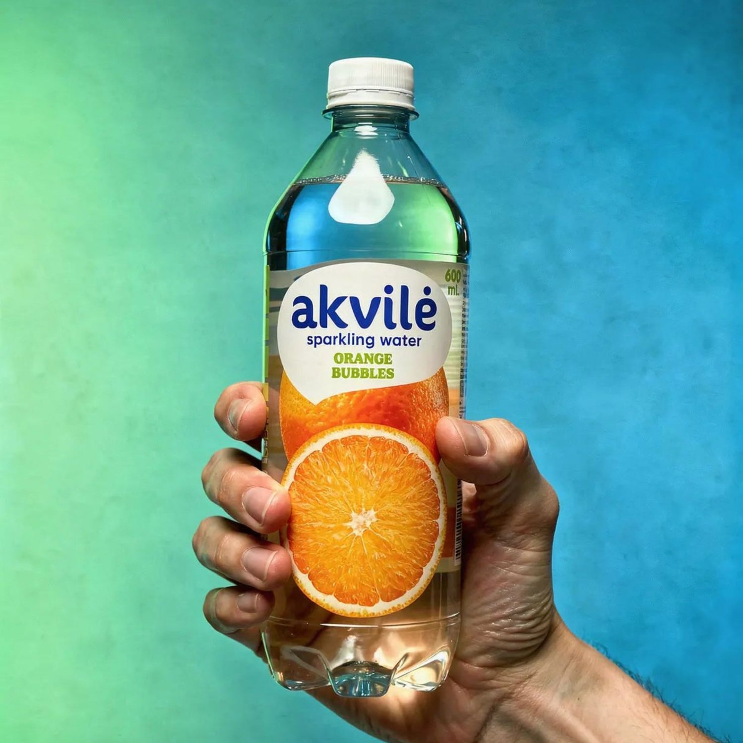 Akvilė Orange lightly sparkling water in a 600ml bottle with a vibrant orange label and clear liquid inside.
