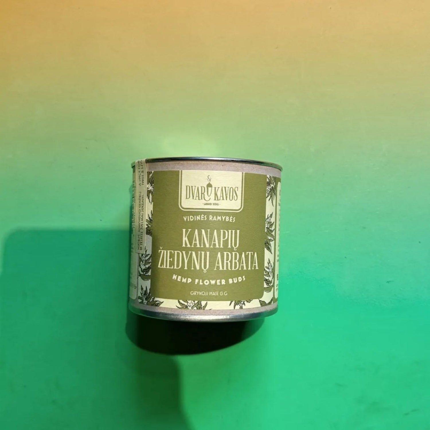 Canister of 'Kanapié Ziedyná Arbata' on a gradient green background