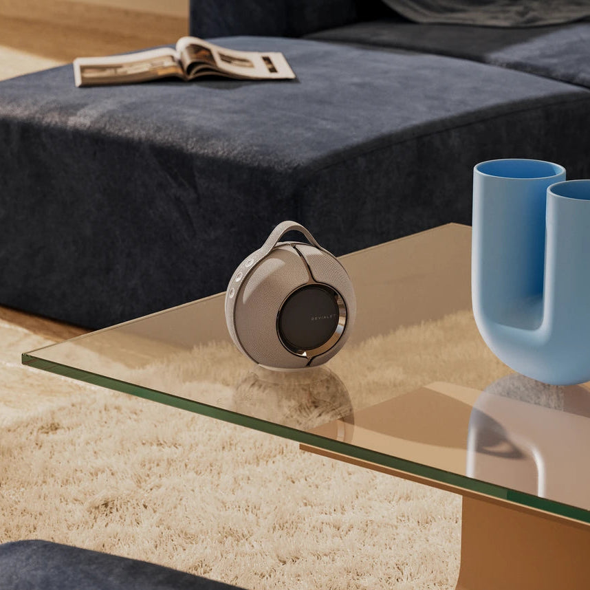 Devialet Mania portable speaker shown in a lifestyle setting with sleek design and compact form factor.