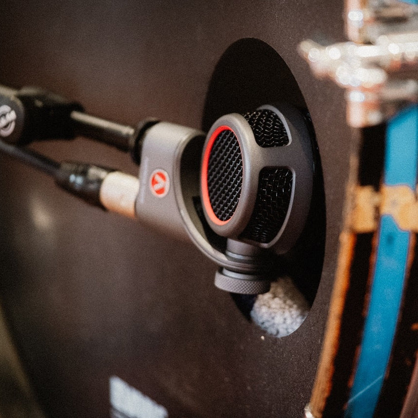 Austrian Audio OC-B6 condenser microphone with black finish and metal grille, positioned on a stand for professional recording.