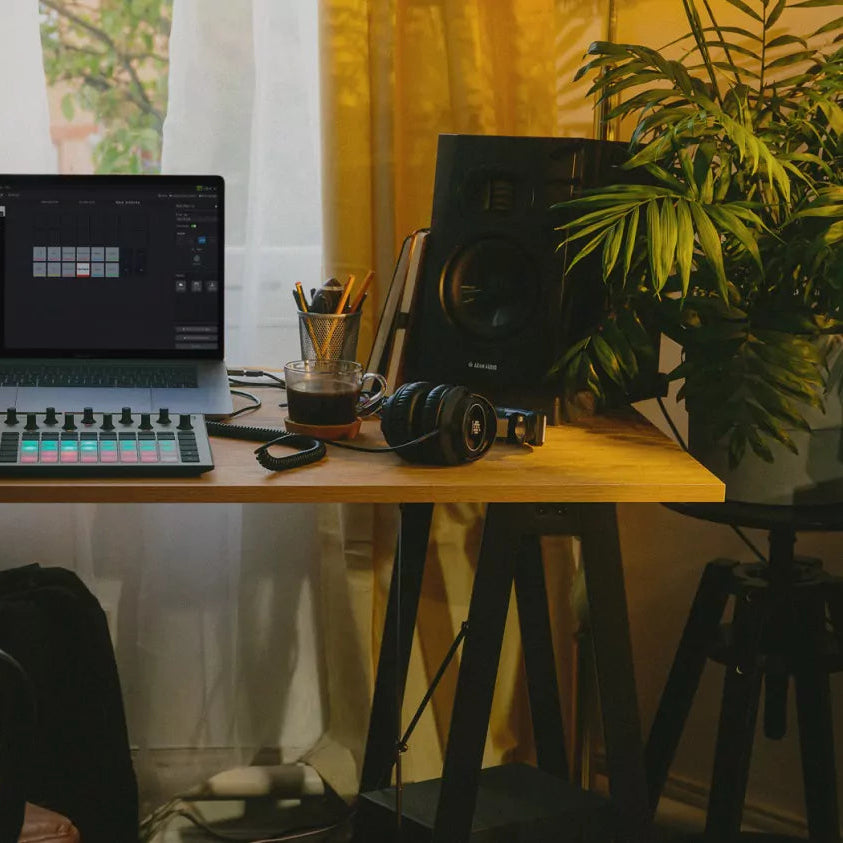 Adam Audio T5V active nearfield studio monitor on a desk with professional audio equipment and acoustic treatment in a studio setting.