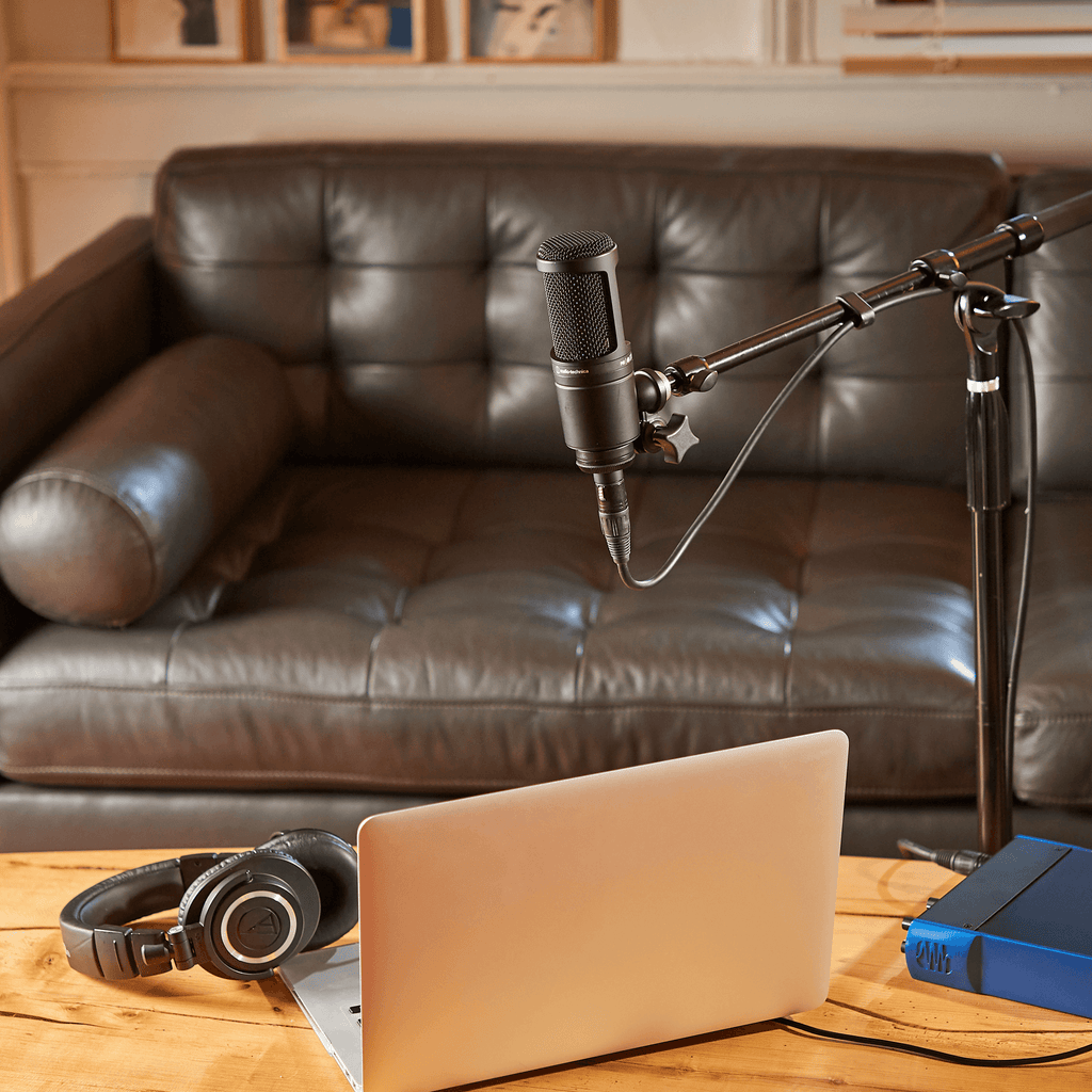 Audio Technica AT 2020 condenser microphone shown in a professional recording setup with a shock mount and pop filter.