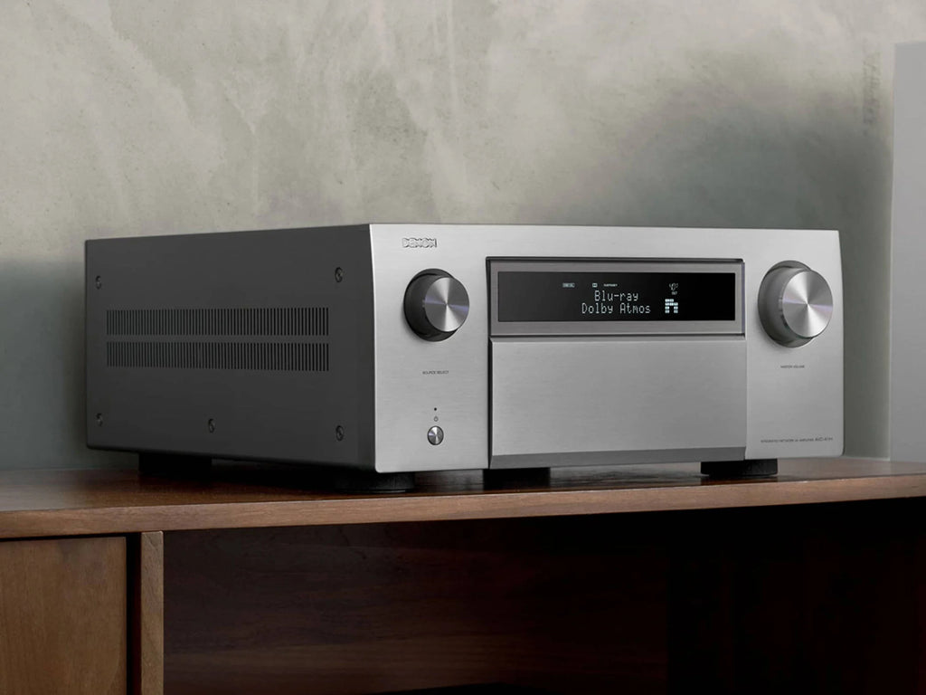 Close-up of the silver Denon AVC-A1H stereo amplifier showing front panel controls and display.