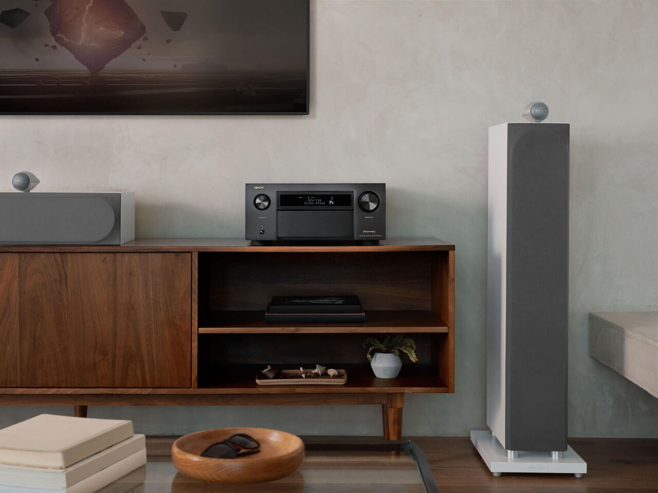 Denon AVC-A1H stereo amplifier with sleek black design and control knobs, shown in a home audio setup.