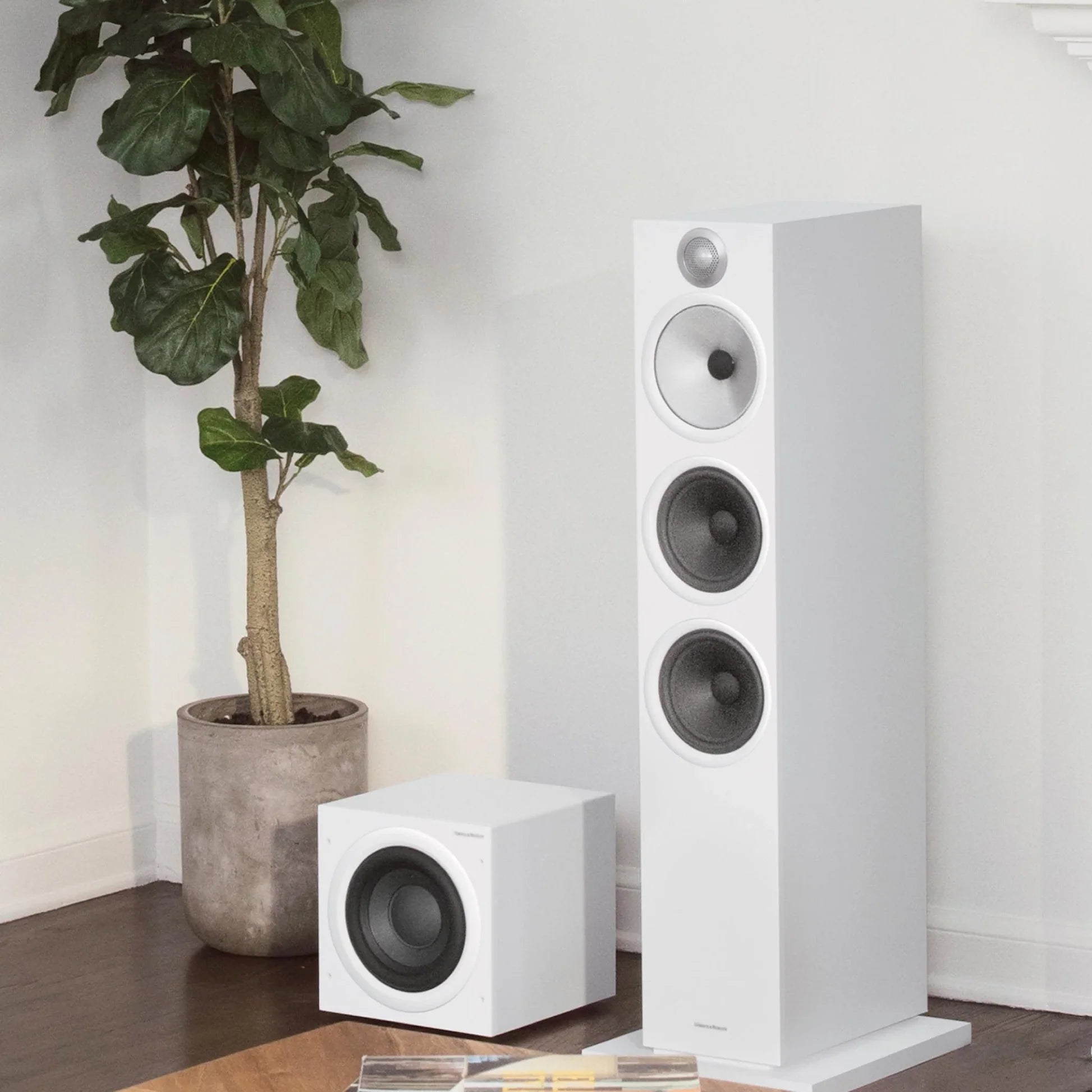 Bowers & Wilkins ASW608 subwoofer in matte white with sleek design, shown in a home audio setup environment