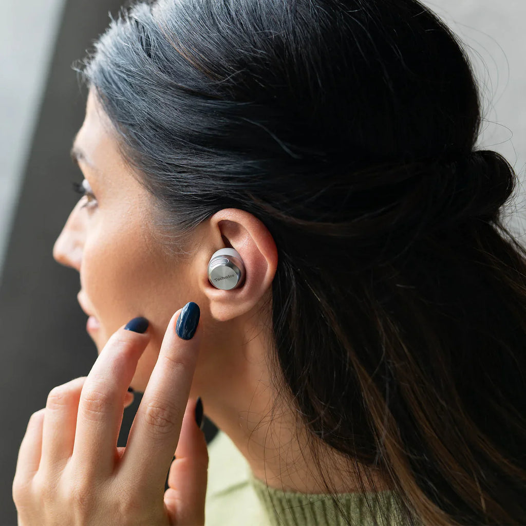 Wireless in-ear headphones by Technics EAH-AZ100 in silver, shown in a lifestyle setting with a sleek, modern design.