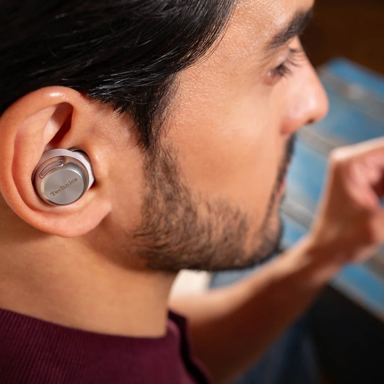 Technics EAH-AZ100 wireless in-ear headphones in silver, shown in a lifestyle setting with a focus on sleek design and compact fit.