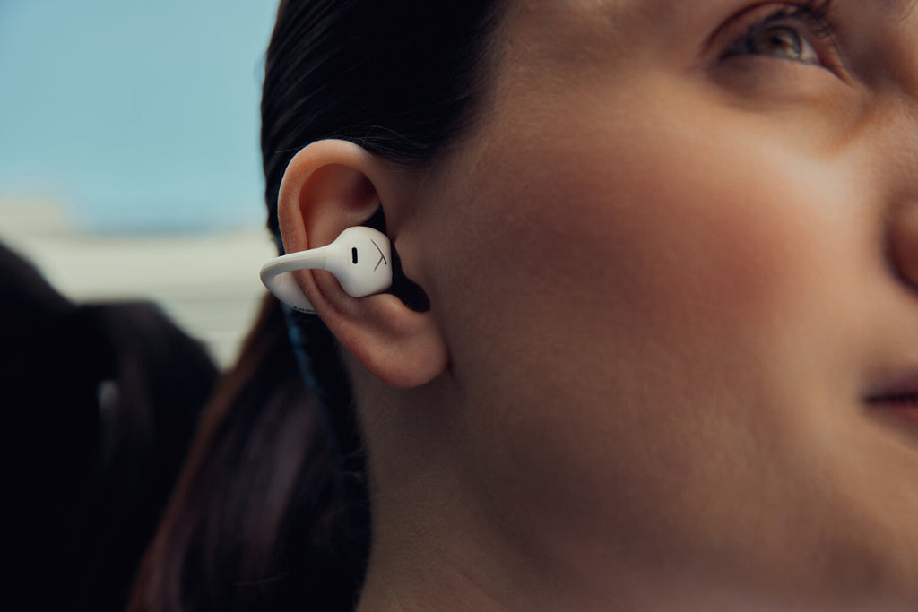 Close-up of Beyerdynamic Amiron Zero wireless in-ear headphones worn by a woman, showcasing sleek white earbud design.