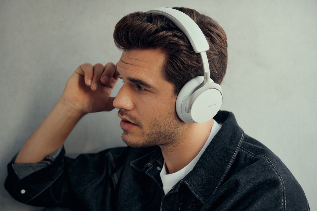 Beyerdynamic Aventho 200 wireless headphones with black ear cups and headband, displayed against a Berlin wall backdrop.
