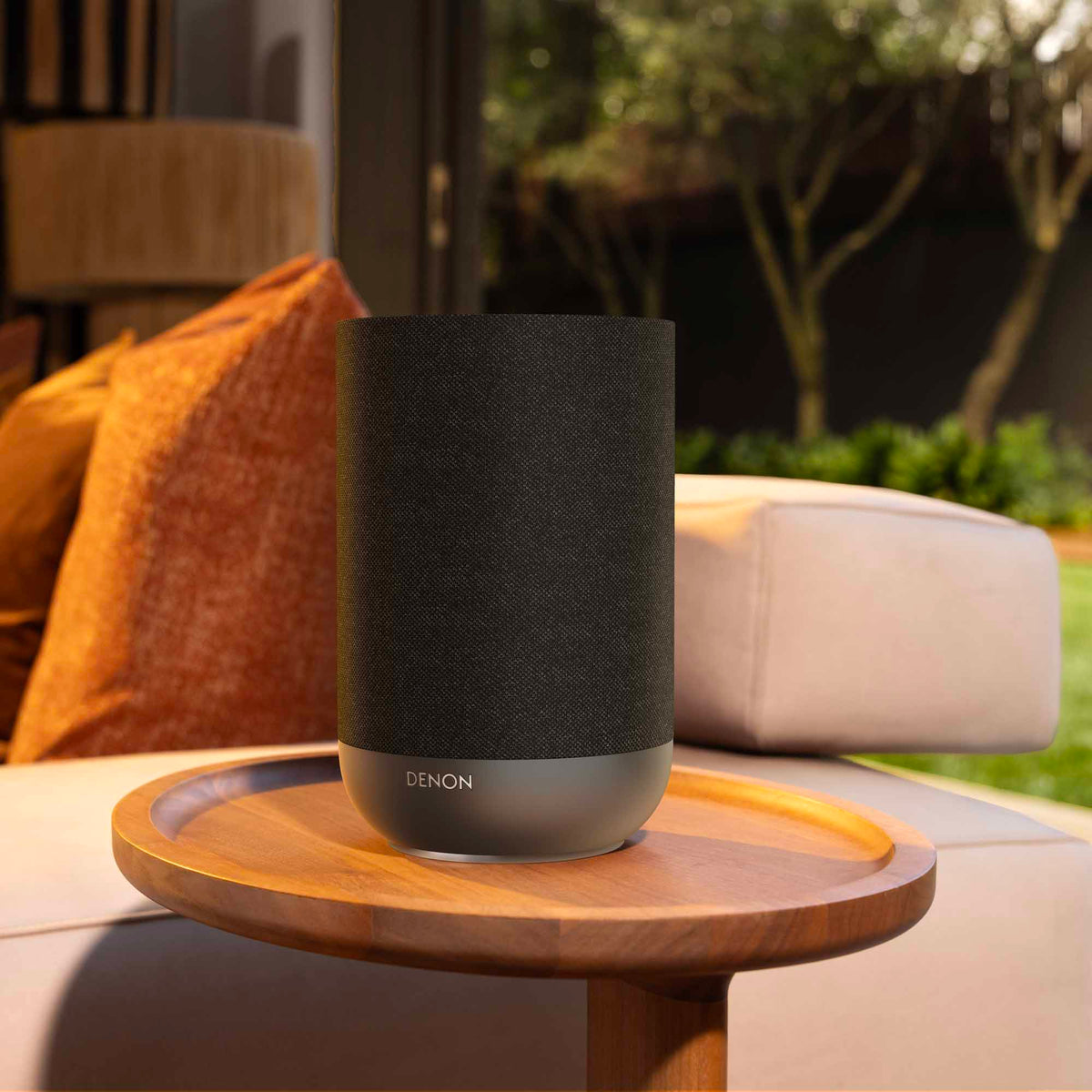 Denon Home 200 wireless speaker in charcoal color, showing a sleek compact design with buttons on top.