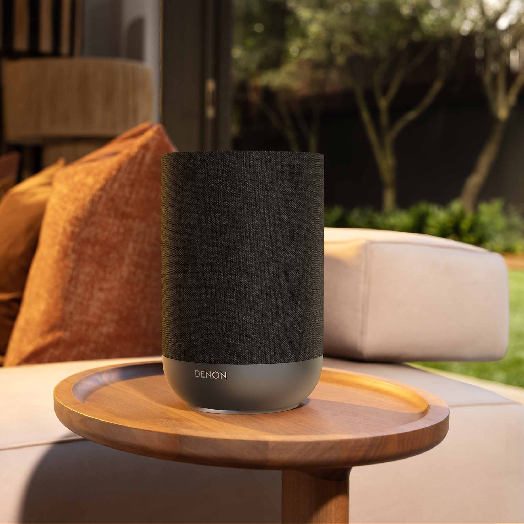 Denon Home 200 wireless speaker in charcoal color, showing a sleek compact design with buttons on top.