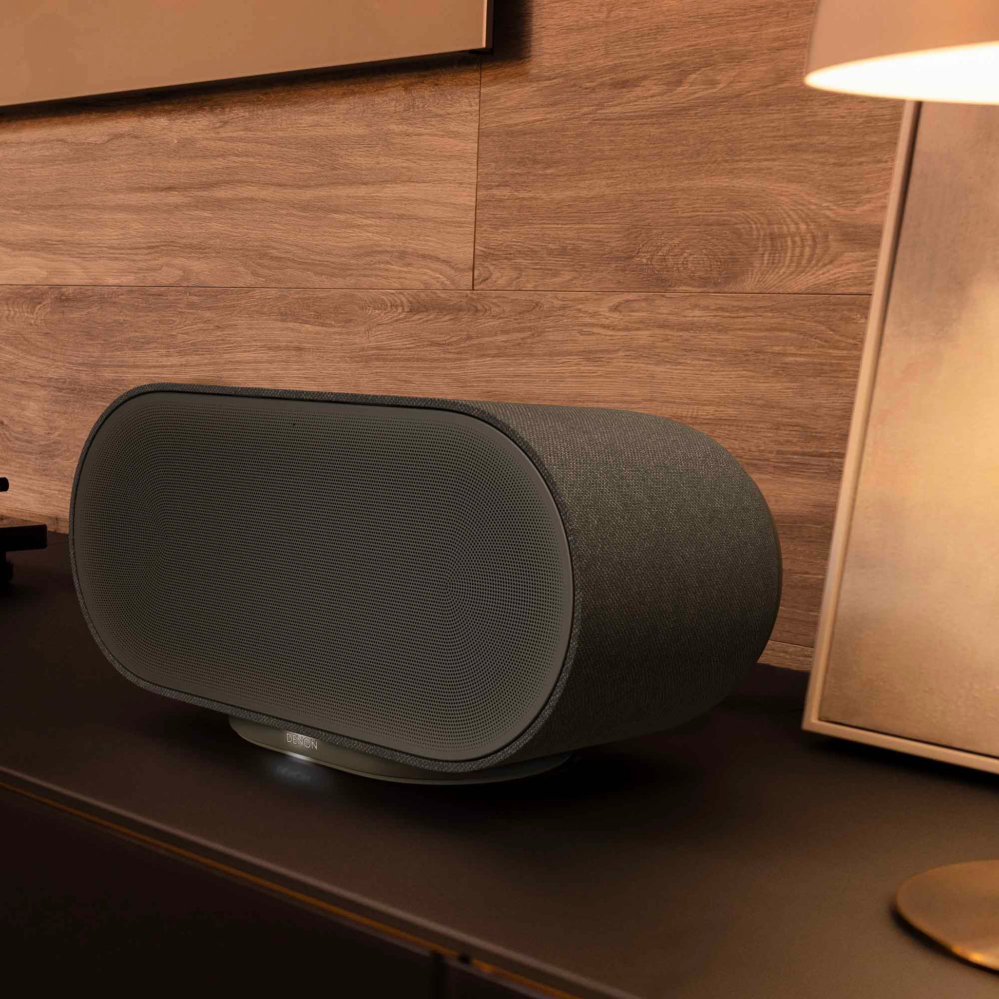 Denon Home 600 wireless speaker in charcoal color, showing a sleek modern design with controls on top.