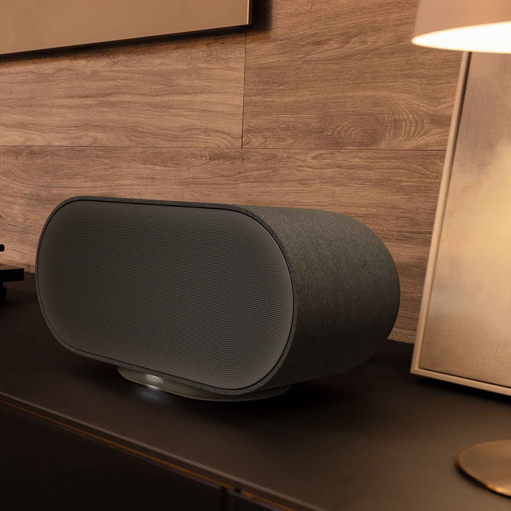 Denon Home 600 wireless speaker in charcoal color, showing a sleek modern design with controls on top.