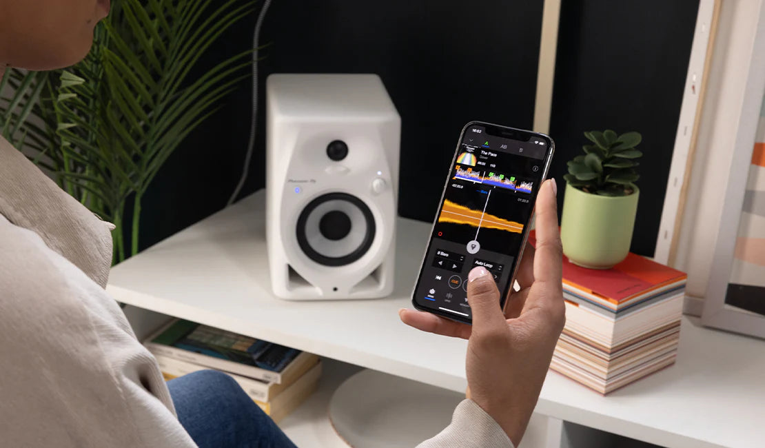 Pioneer DJ DM-40D-BT desktop speakers shown in a modern home setup with sleek black design and compact form factor.