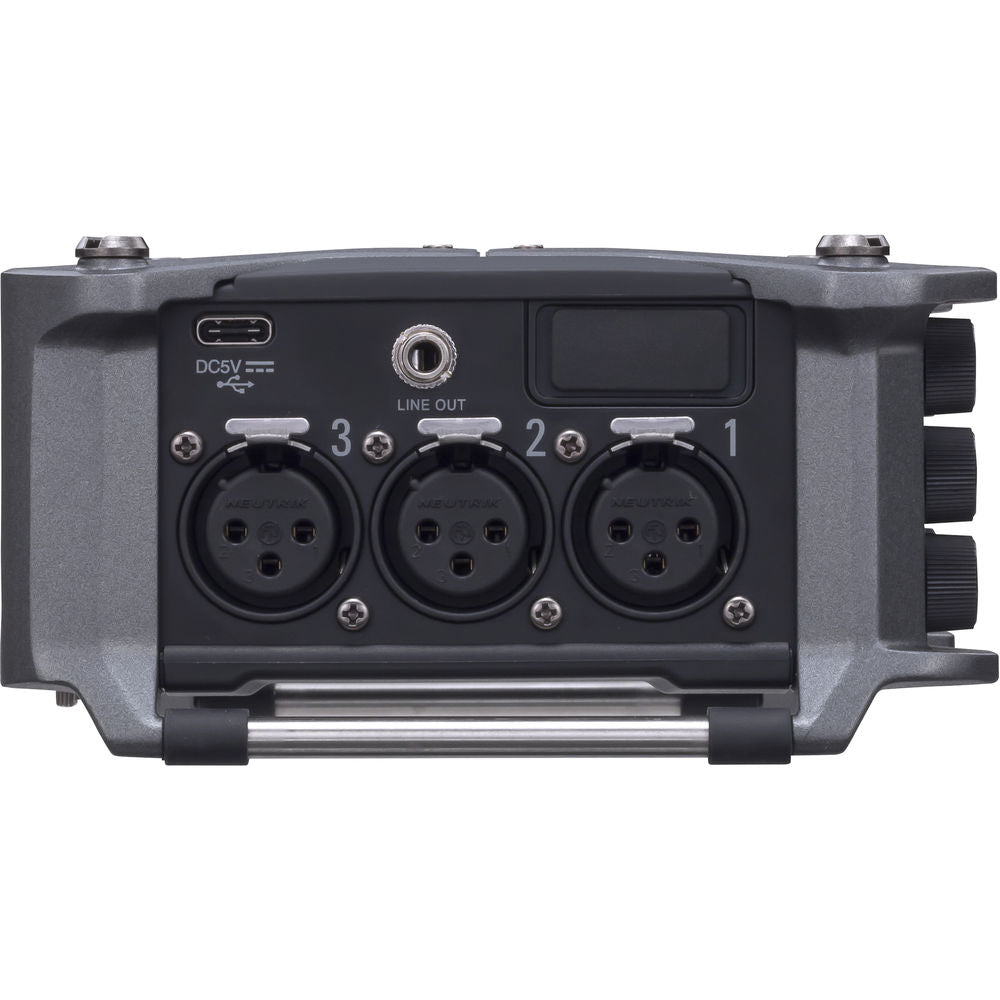 Zoom F6 digital recorder with multiple input ports and LCD screen, shown in a professional audio recording setup.