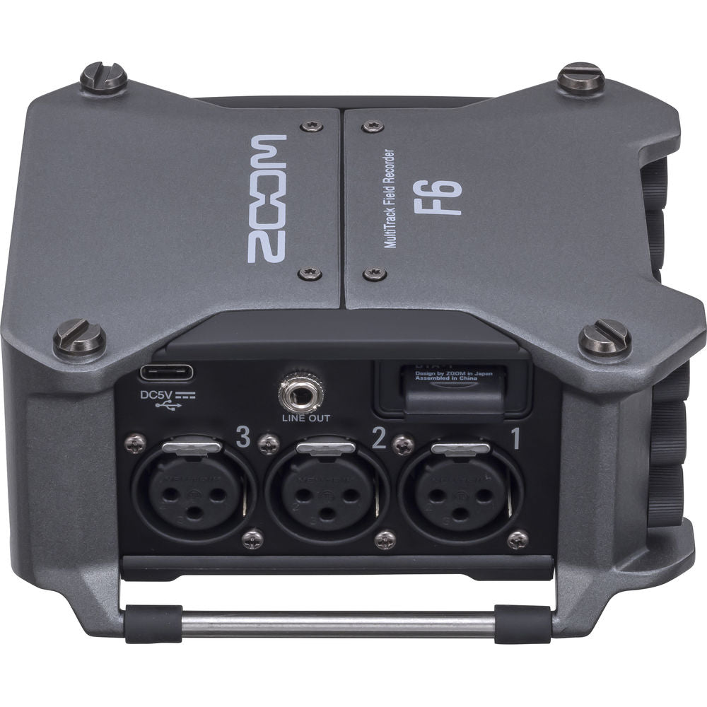 Zoom F6 digital recorder with multiple input ports and display screen, shown on a table with accessories.