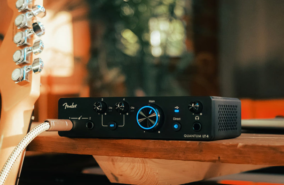 Fender Quantum LT 4 on a wooden desk with guitar — Soundium homepage