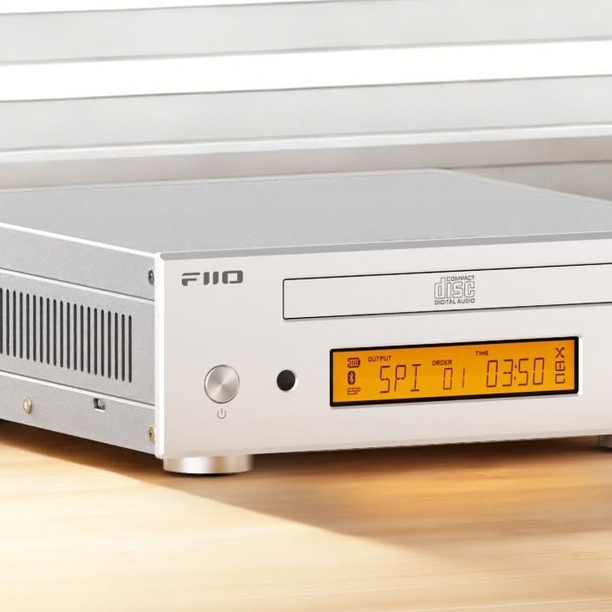 FiiO DP11 silver CD player on a wooden desk, close-up of the display